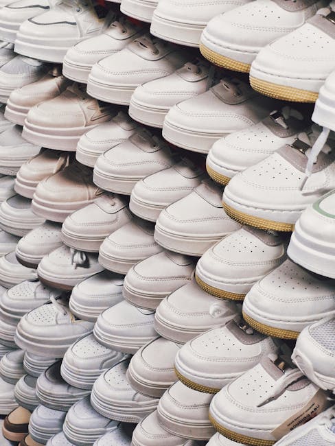 A large collection of white sneakers neatly arranged in a shoe store display.